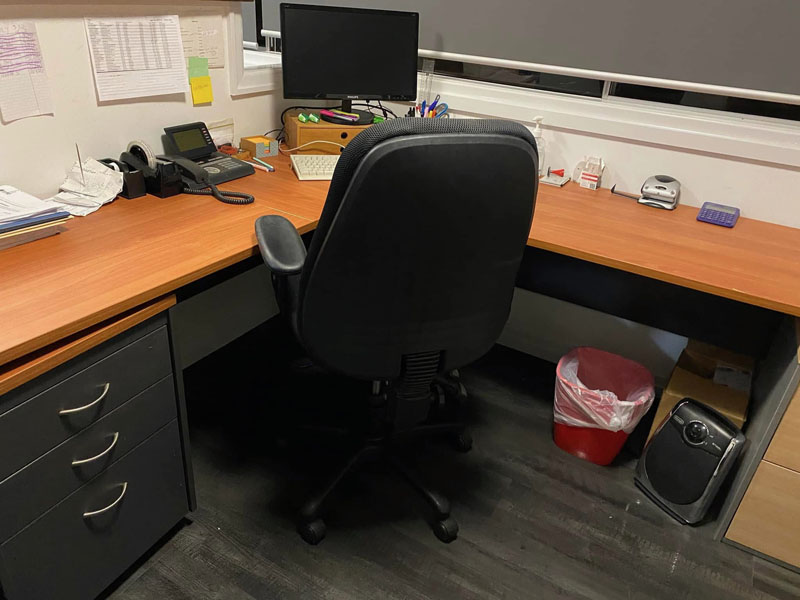 Corner office desk with a black office chair, phone and computer