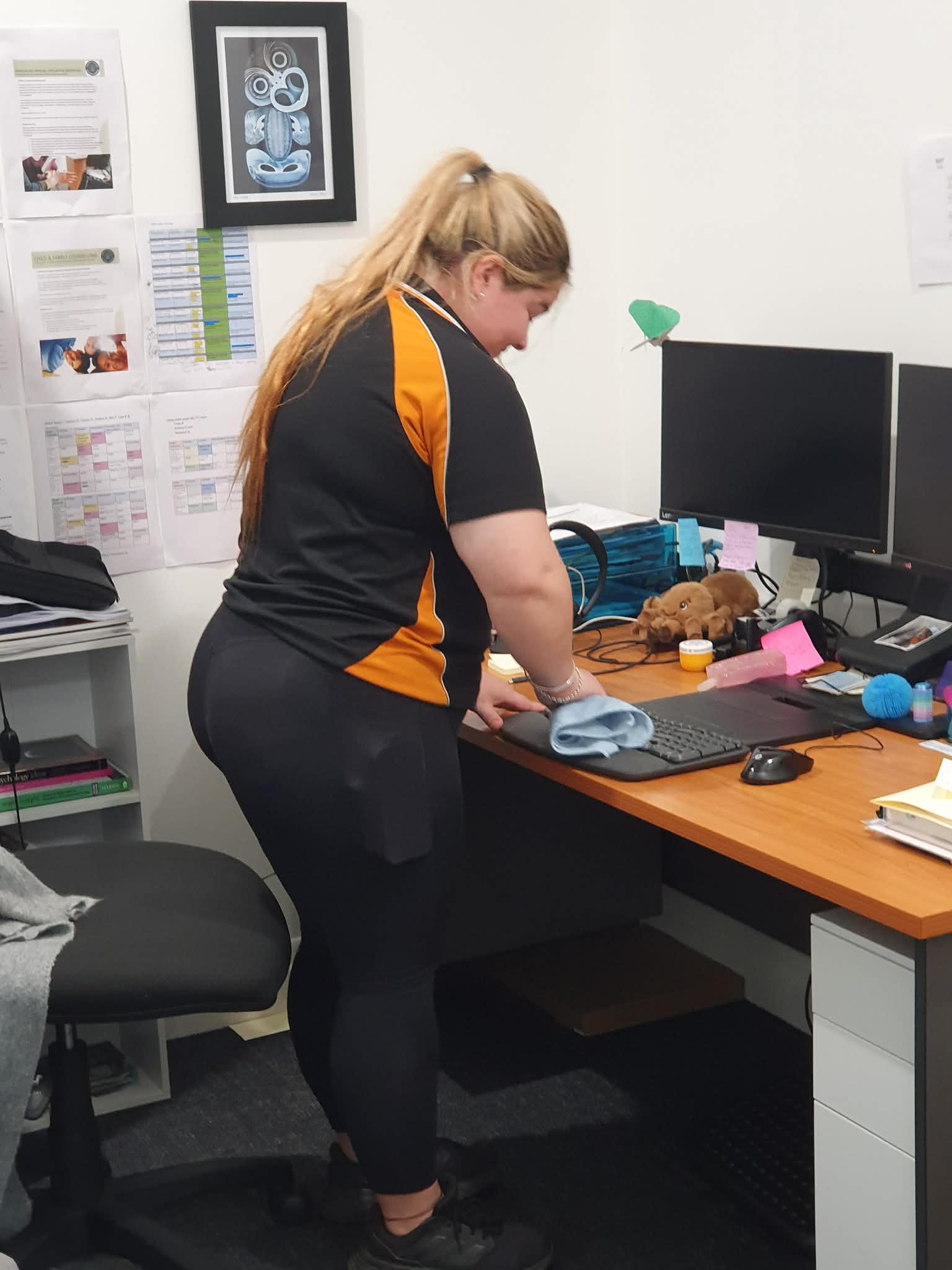 Cleaner wiping a computer keyboard at an office desk